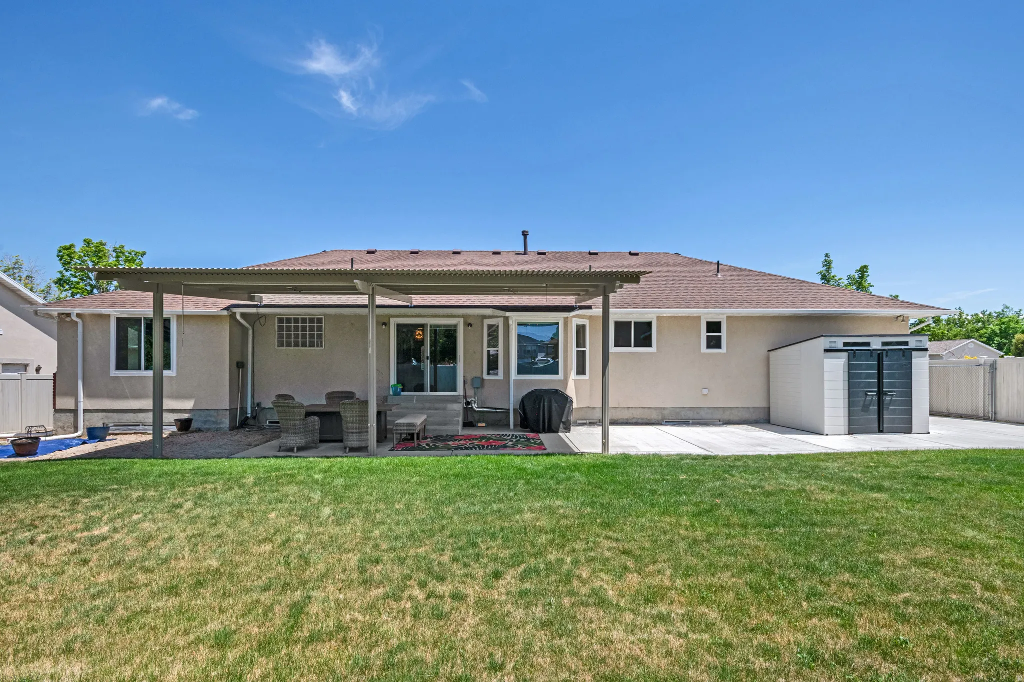 Expansive grass lawn backyard with a covered patio featuring a concrete slab