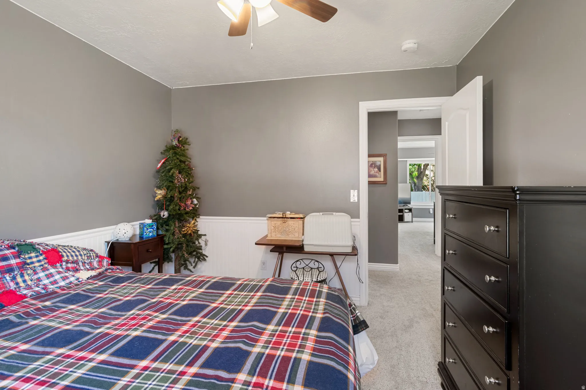 Bedroom featuring neutral gray walls, white wainscoting, and light-colored carpet flooring