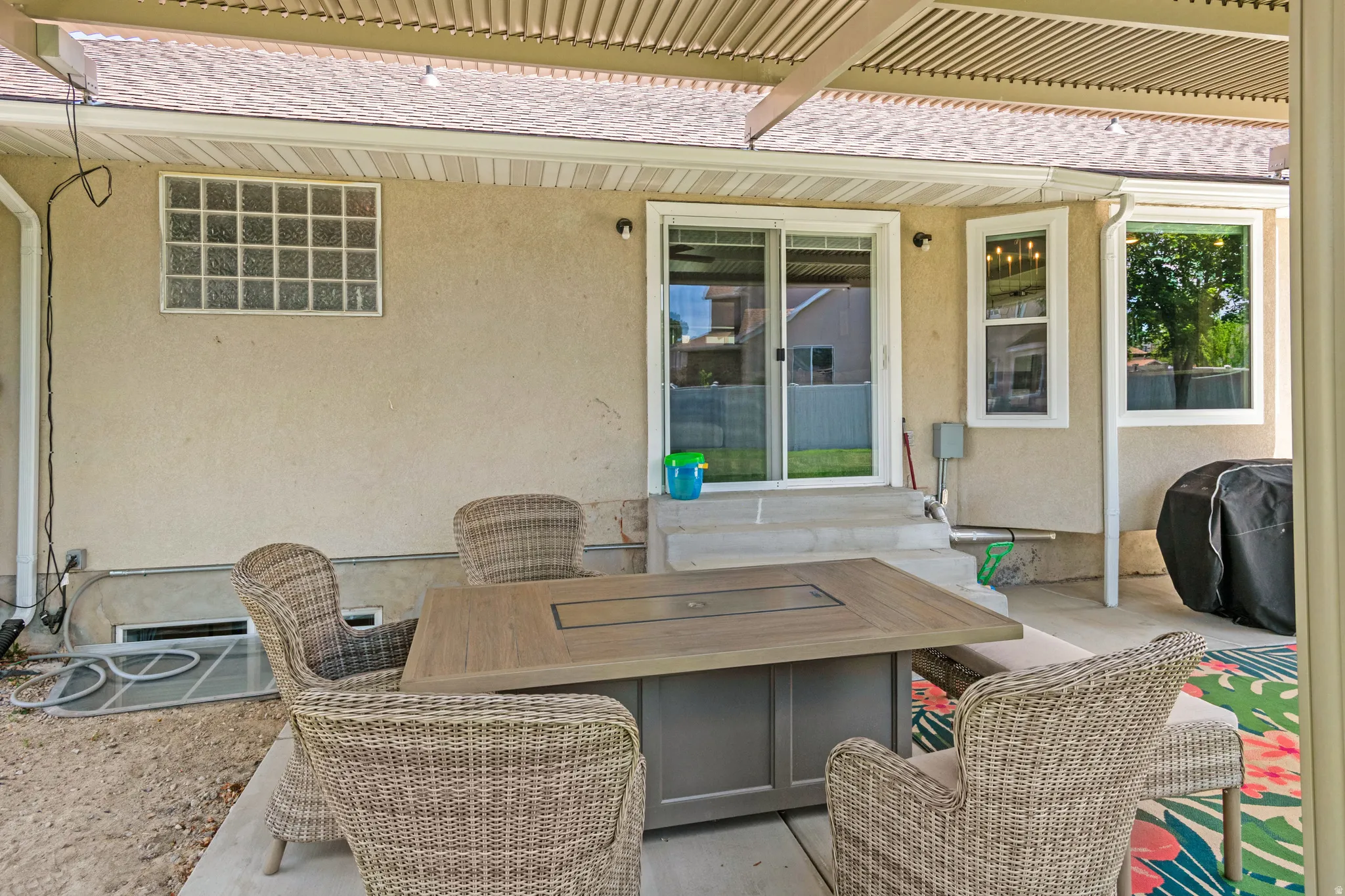 Covered patio featuring a slatted roof structure, stucco exterior, and a sliding glass door entry