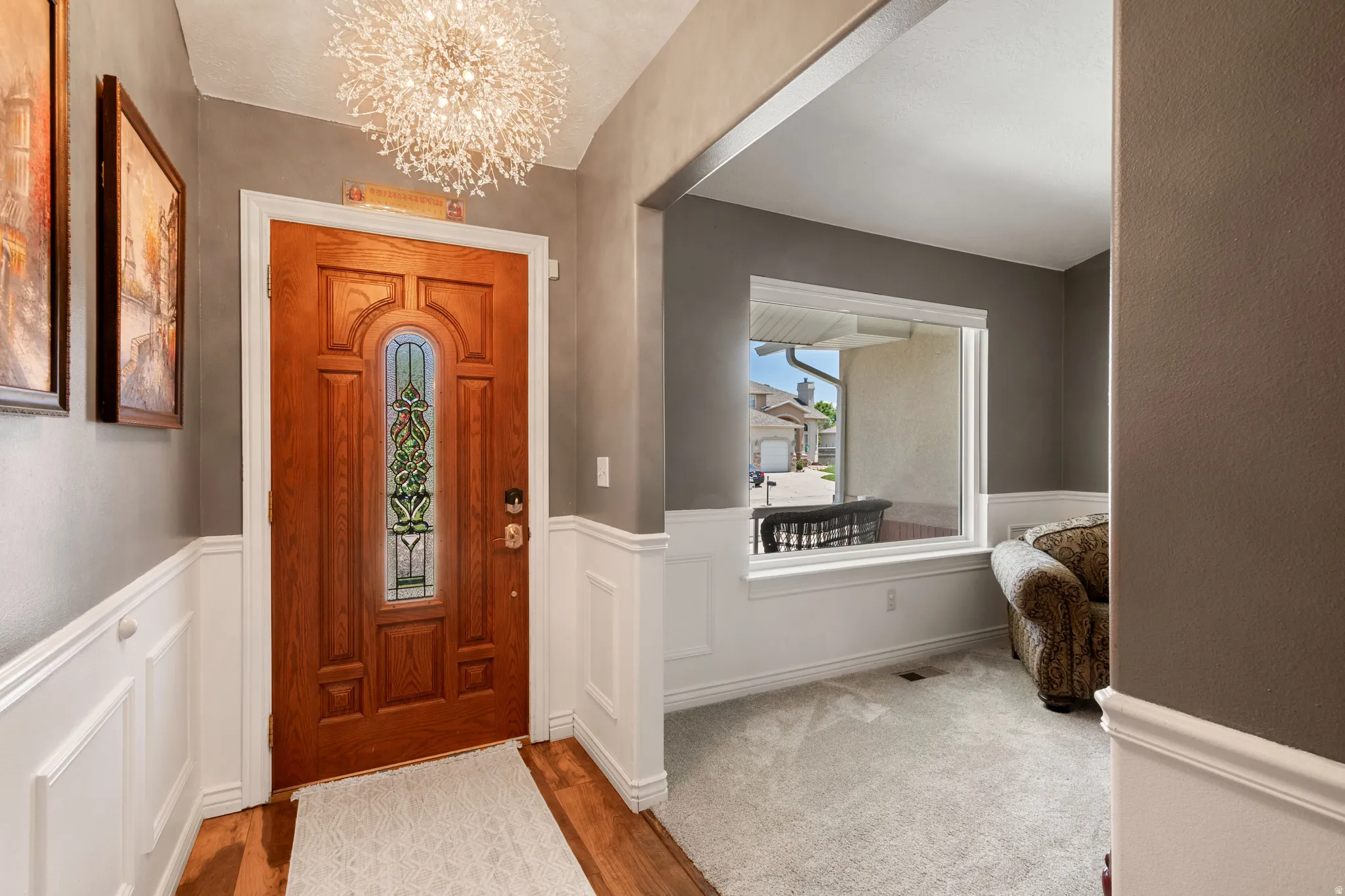 Entryway featuring a wood-panel door with decorative glass inlay, wood-finish flooring, and a contemporary chandelier