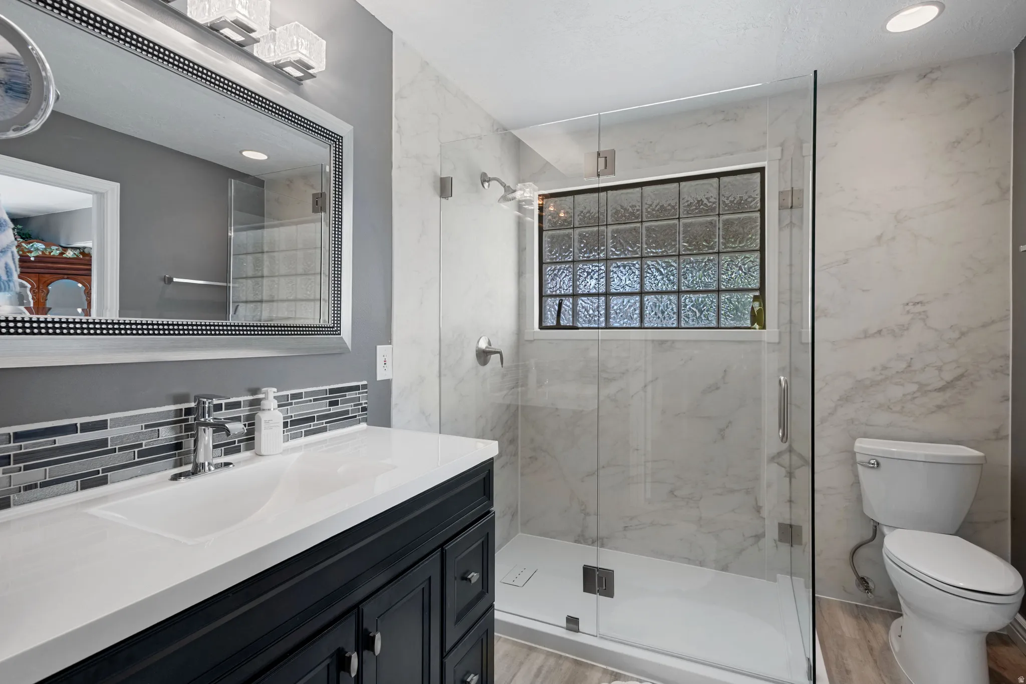 Bathroom vanity featuring a white countertop with an undermount sink, mosaic tile backsplash, and a framed mirror