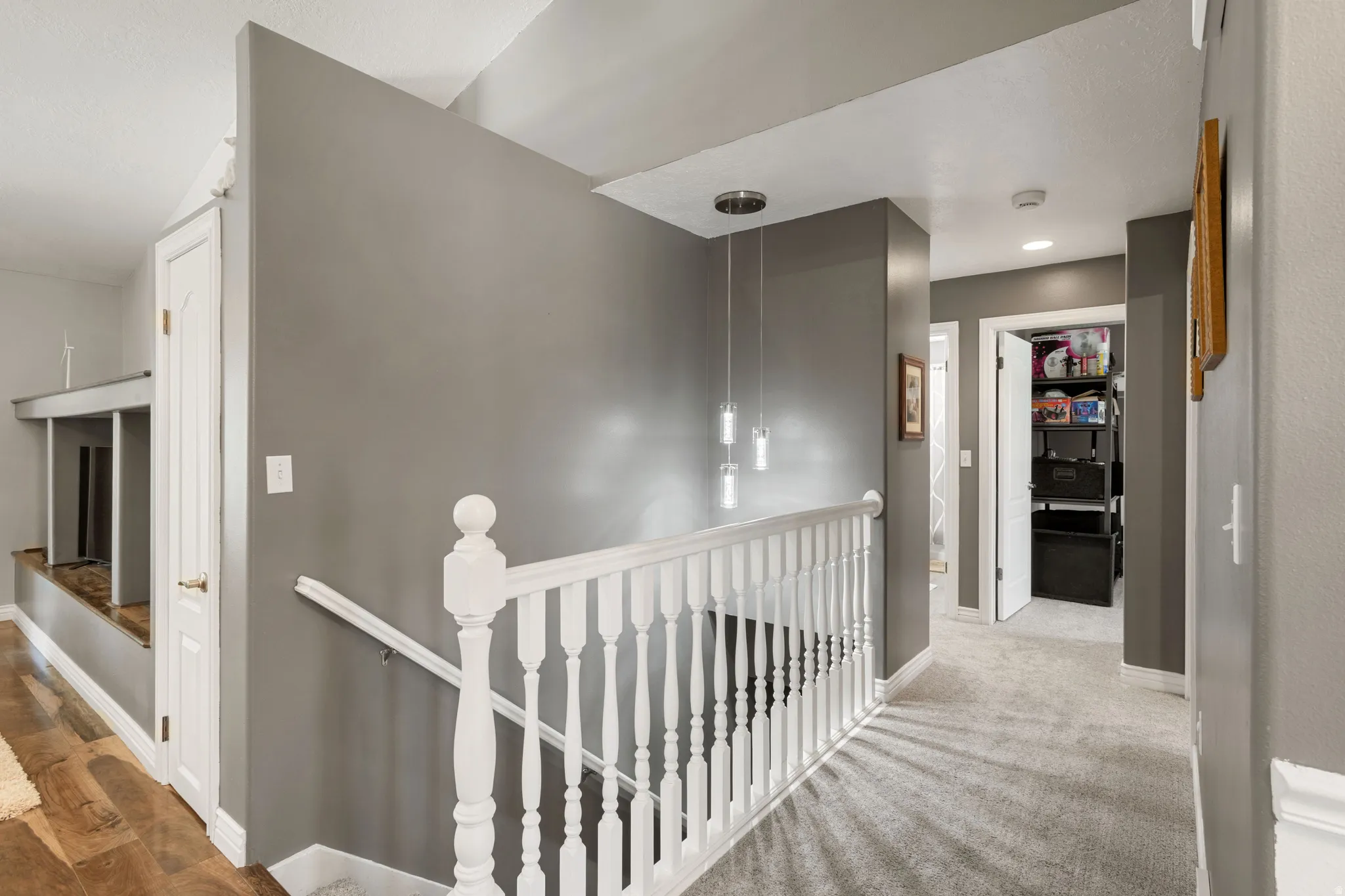 Upper-level hallway featuring a white baluster railing, gray wall paint, and a built-in shelving unit