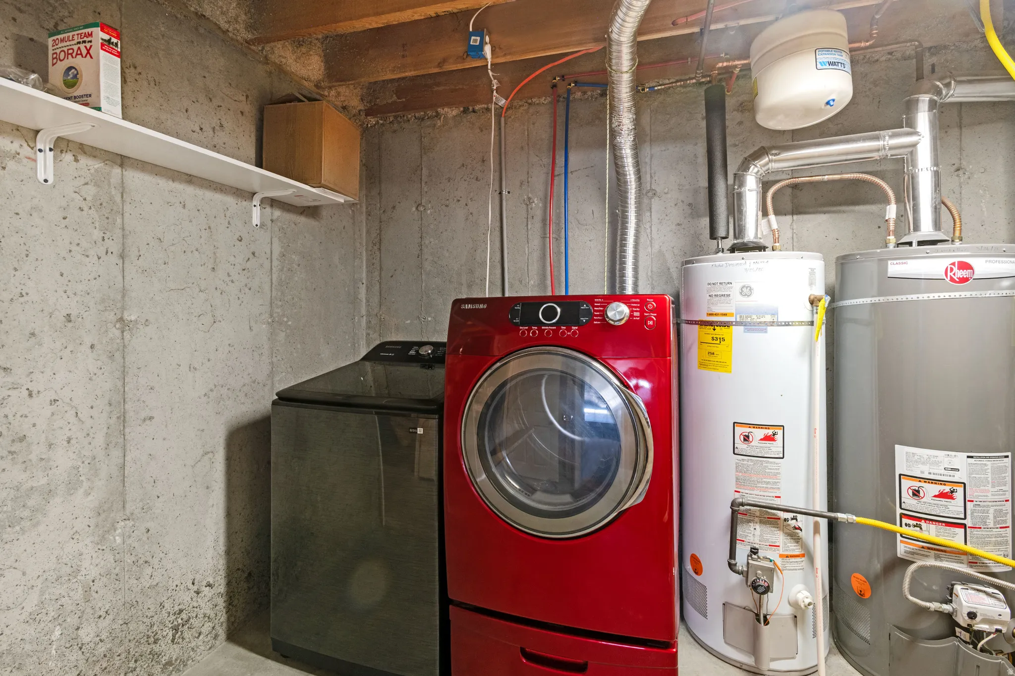 Utility area featuring a built-in shelf, two water heaters, and exposed ceiling joists