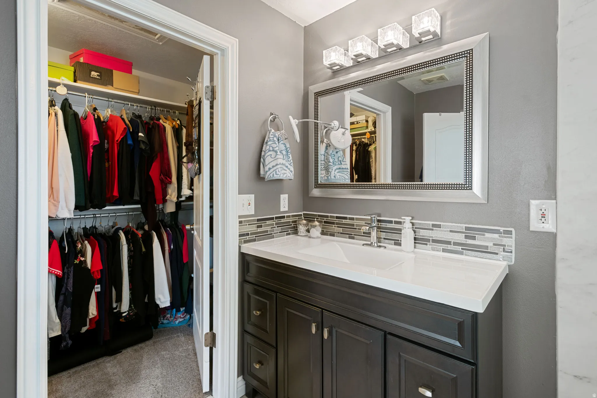 Bathroom vanity featuring a single sink, dark wood-finish cabinetry, and a mosaic tile backsplash