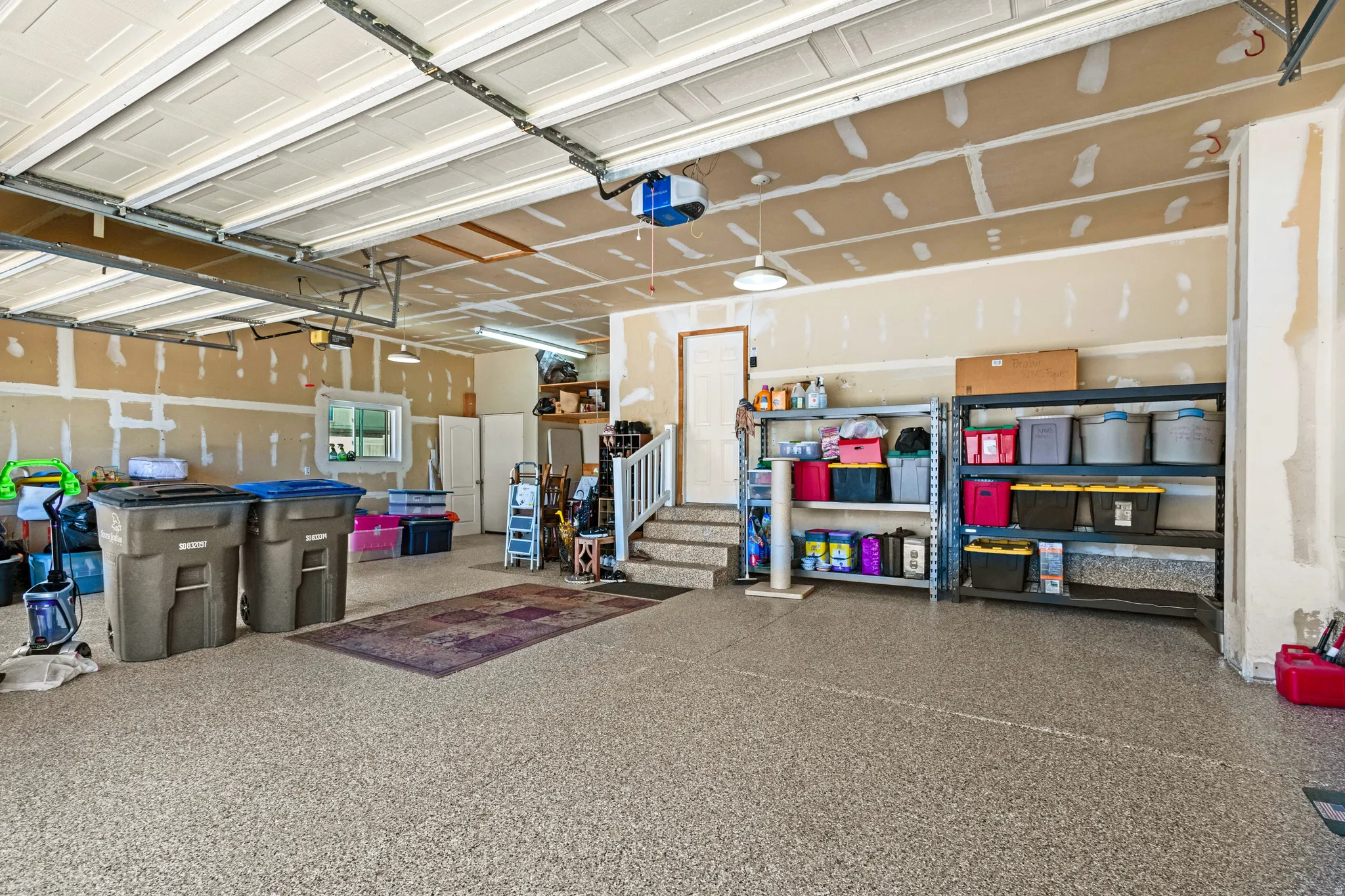 Spacious multi-car garage featuring an epoxy-coated concrete floor, recessed lighting, and a window for natural light