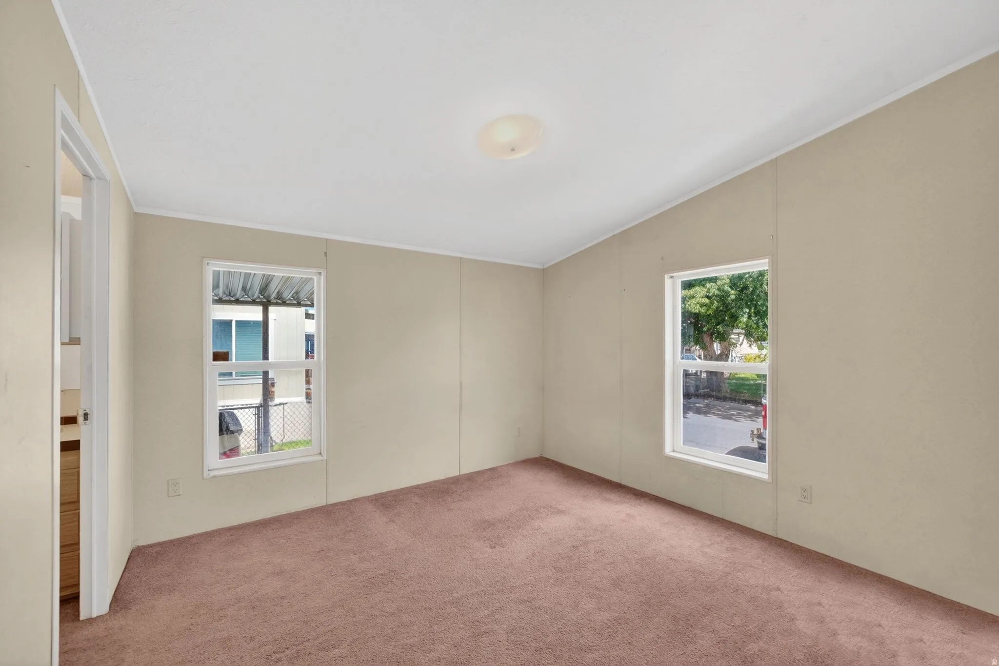 Carpeted room featuring two windows, pale beige walls, white trim, and a ceiling light fixture
