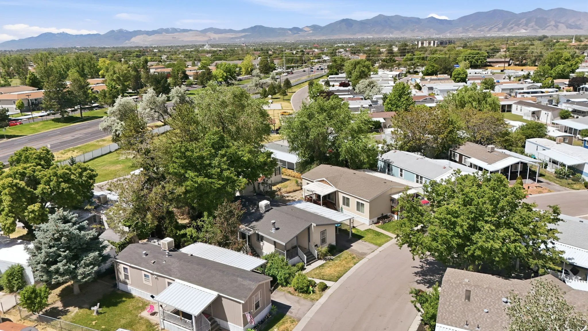 Community aerial showcasing residential units with pitched roofs and surrounding mature trees