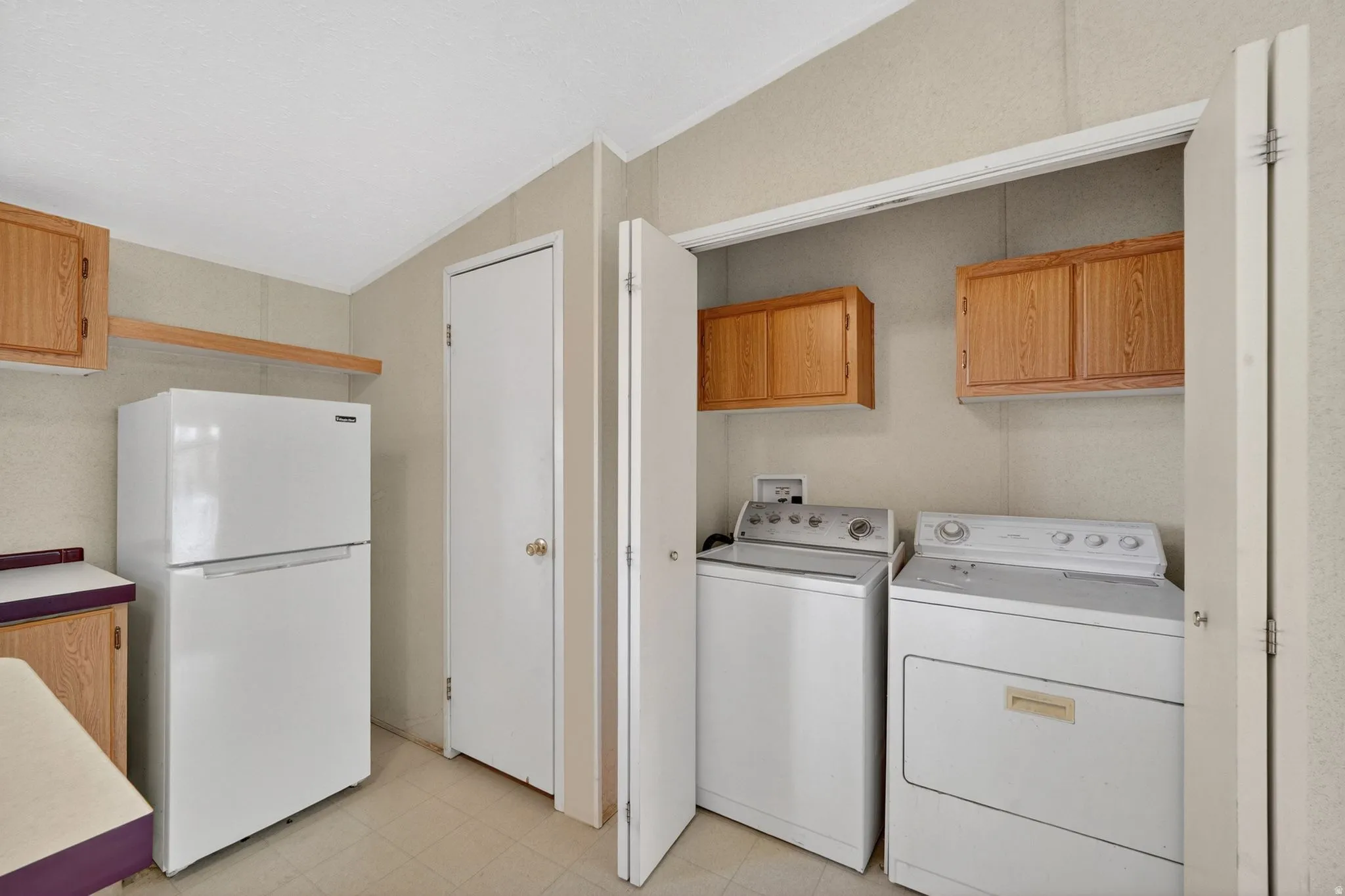Dedicated laundry closet featuring a washer and dryer, accompanied by overhead cabinetry for storage