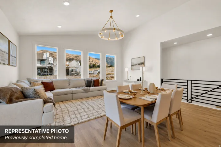Open concept living and dining area featuring a vaulted ceiling and wood-finish flooring