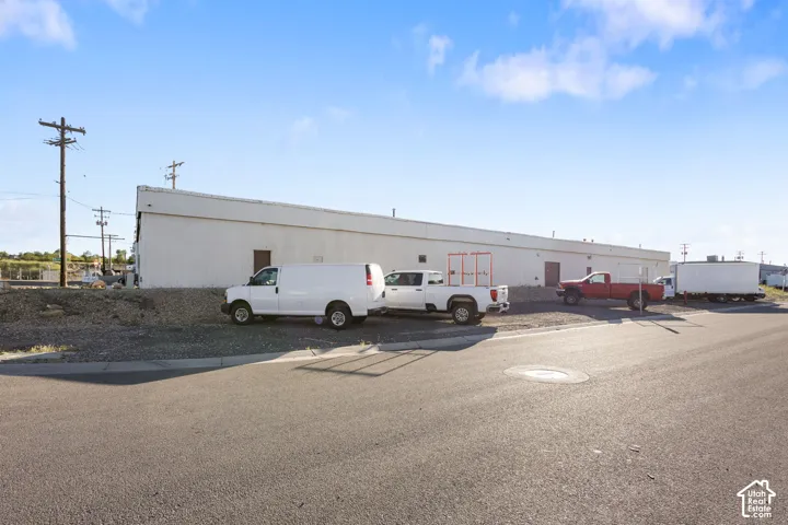 White industrial building with multiple entry doors and a gravel parking area