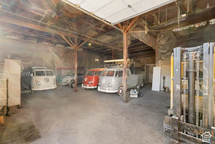 Spacious interior warehouse featuring a concrete floor, exposed wood beam ceiling structure, and high overhead door