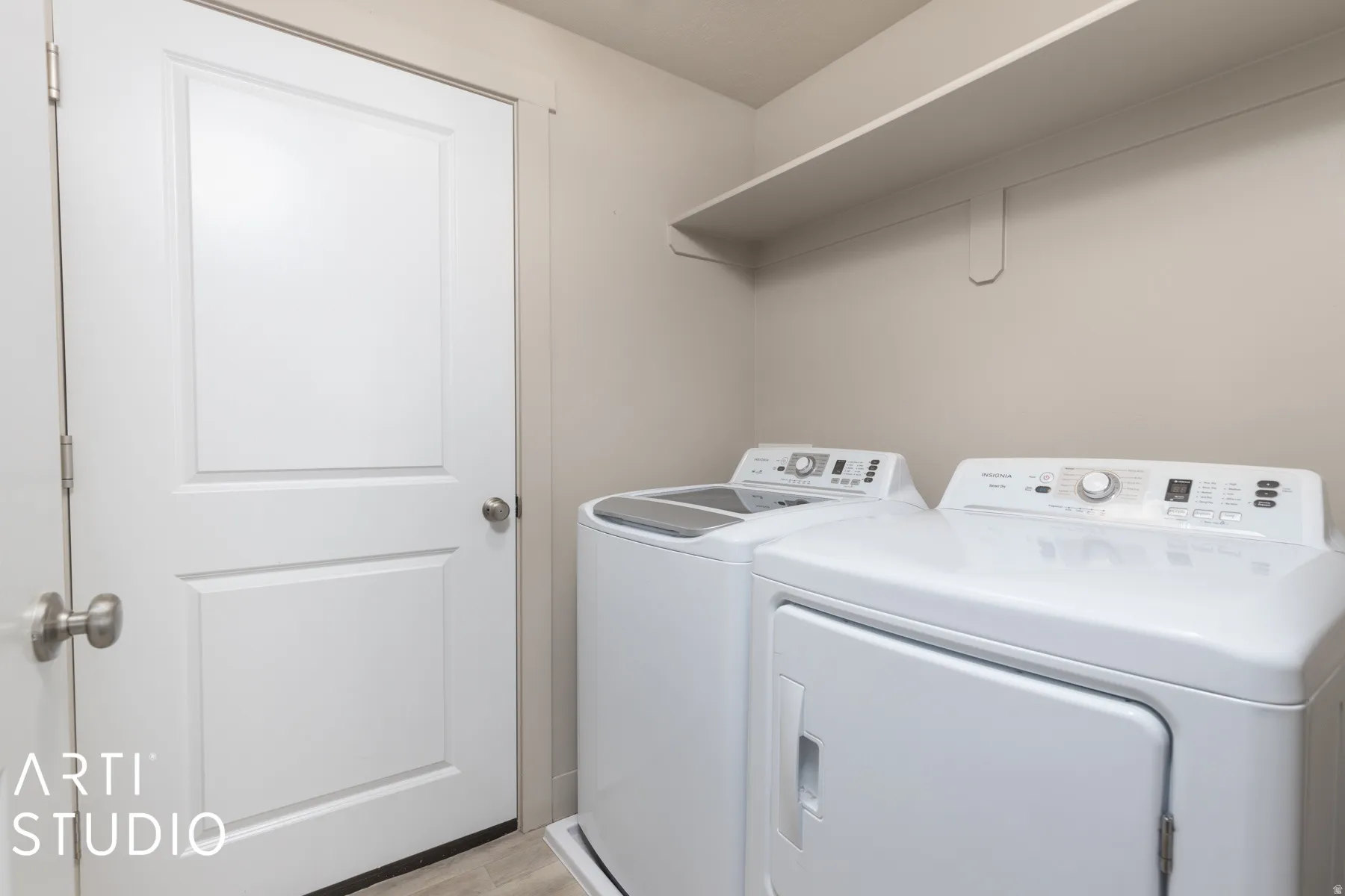Dedicated laundry area featuring a built-in shelving unit, neutral wall paint, and wood-finish flooring