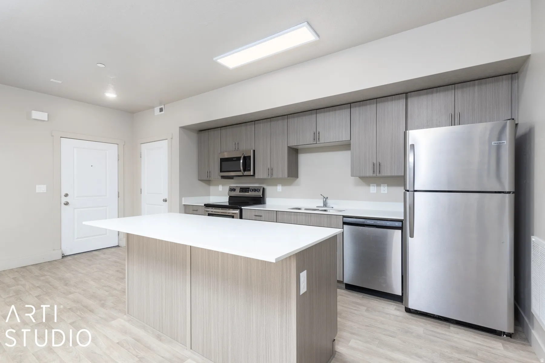 Kitchen featuring a central island with white countertop, grey wood-finish cabinetry, stainless steel appliances, and wood-look flooring