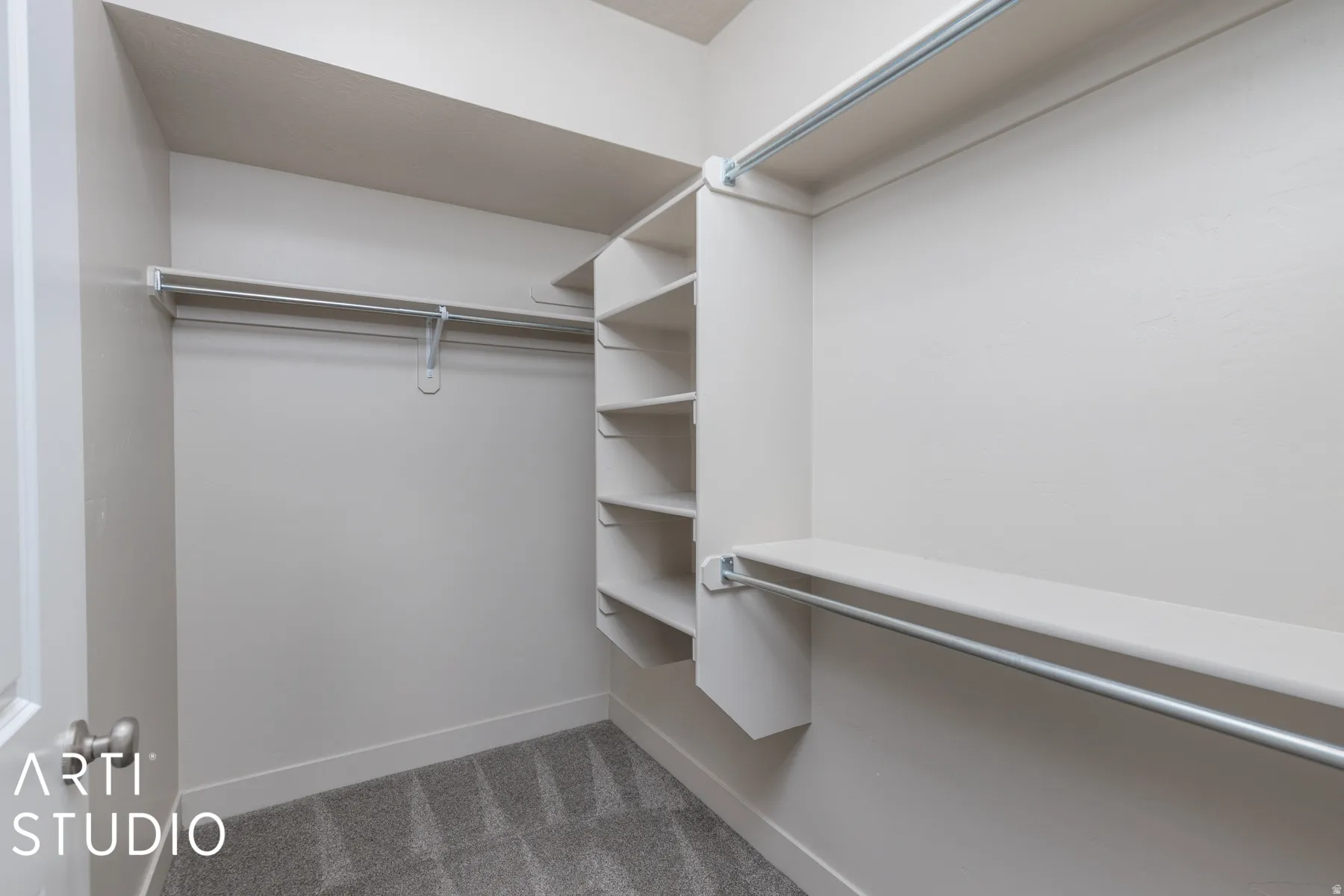 Walk-in closet featuring built-in shelving, multiple hanging rods, white walls, white trim, and gray patterned carpet