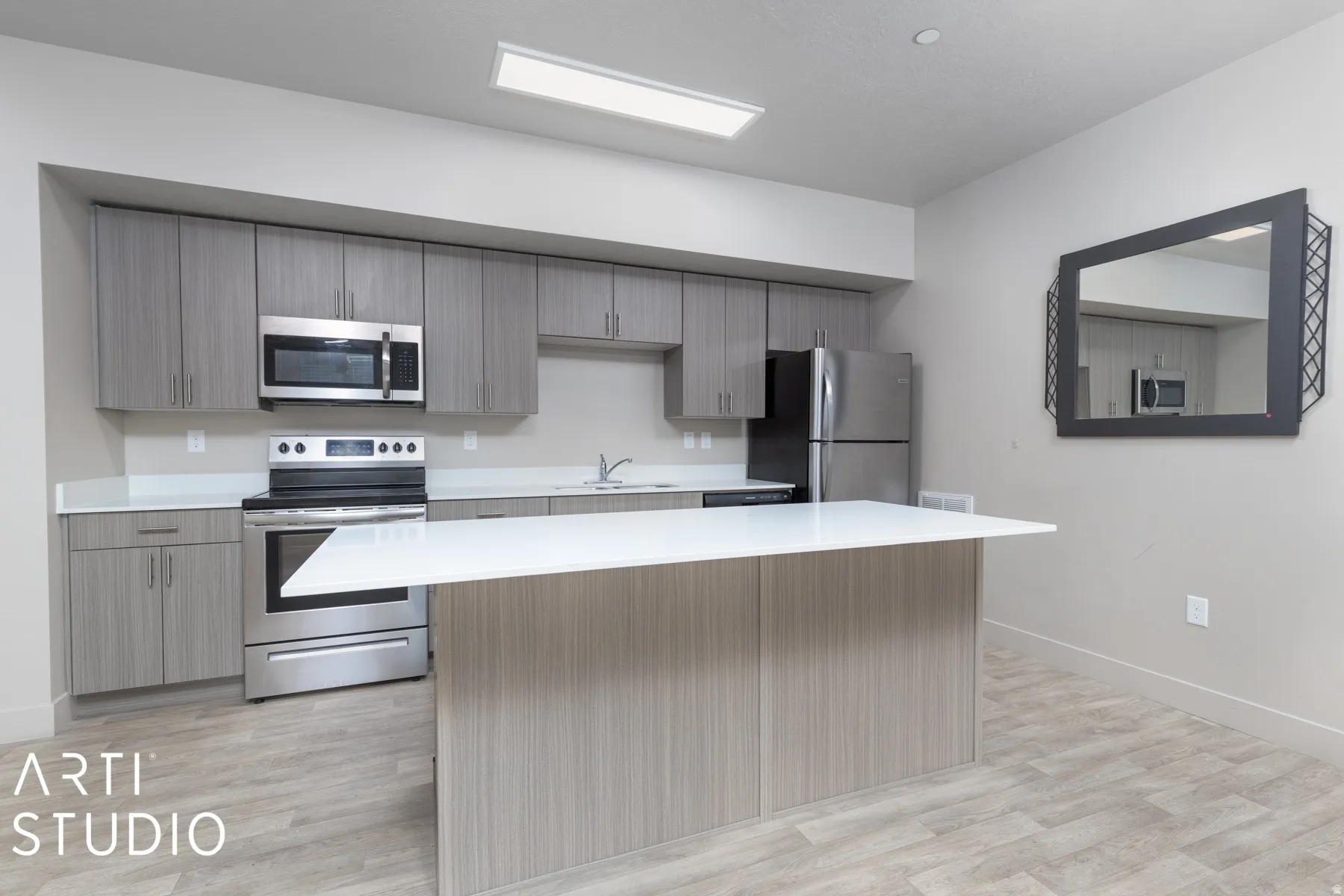 Modern kitchen featuring an expansive island with white countertop, full suite of stainless steel appliances, grey wood-finish cabinetry, and wood-finish flooring