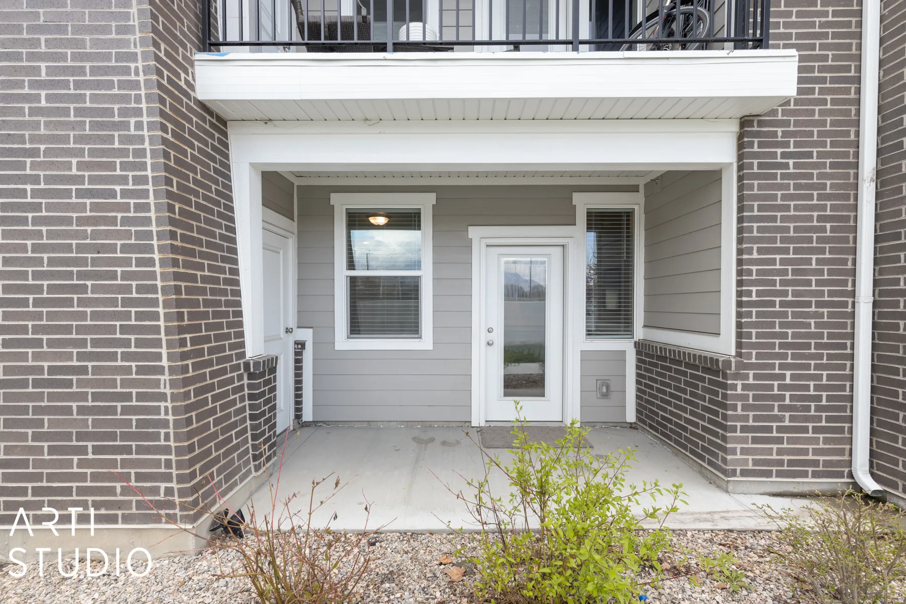 Entryway featuring a glass-paned door, a concrete patio, and gray siding
