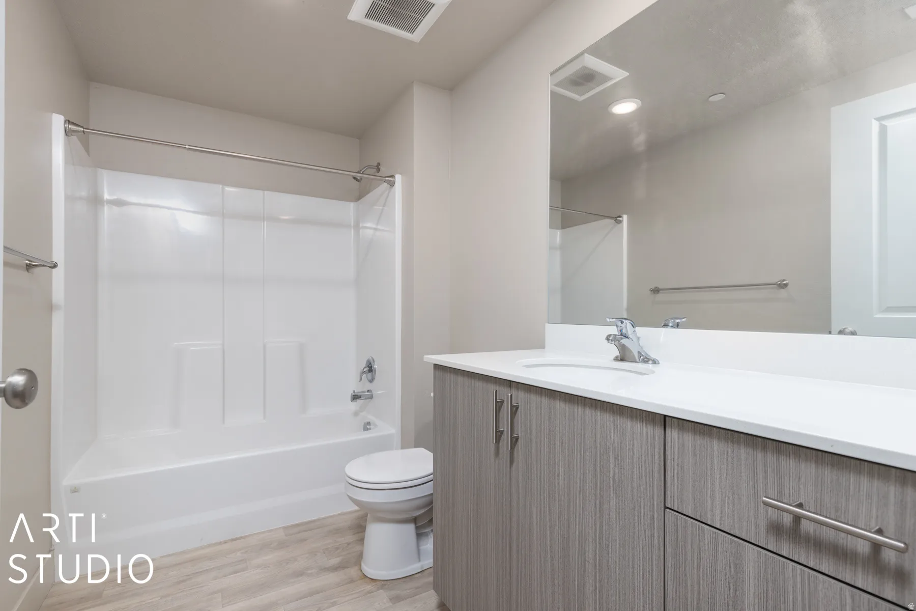 Bathroom featuring a white tub and shower combination, a single vanity with wood-finish cabinetry, white countertop, and a large wall-mounted mirror