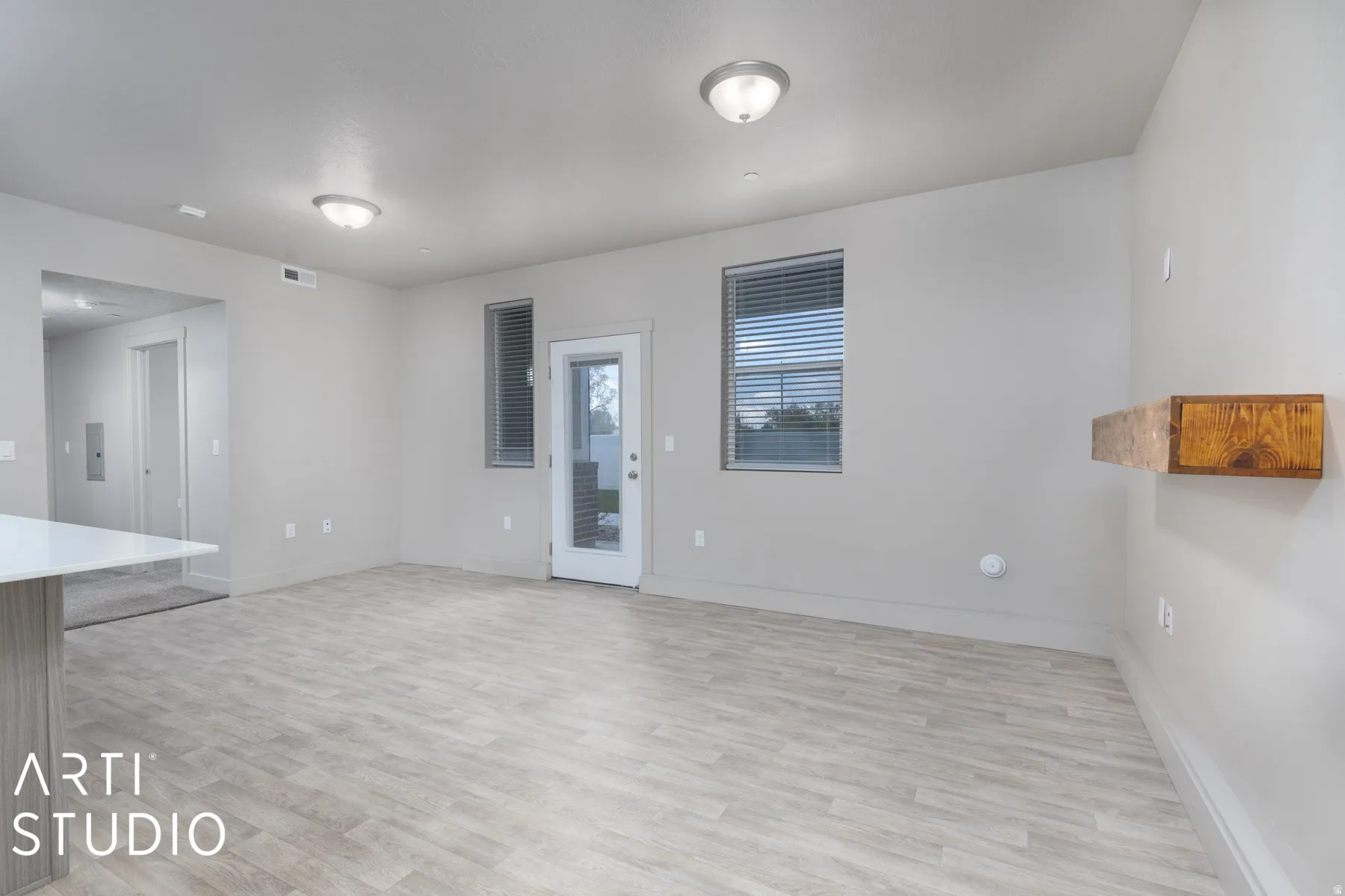 Spacious living area featuring light wood-finish flooring and neutral wall tones