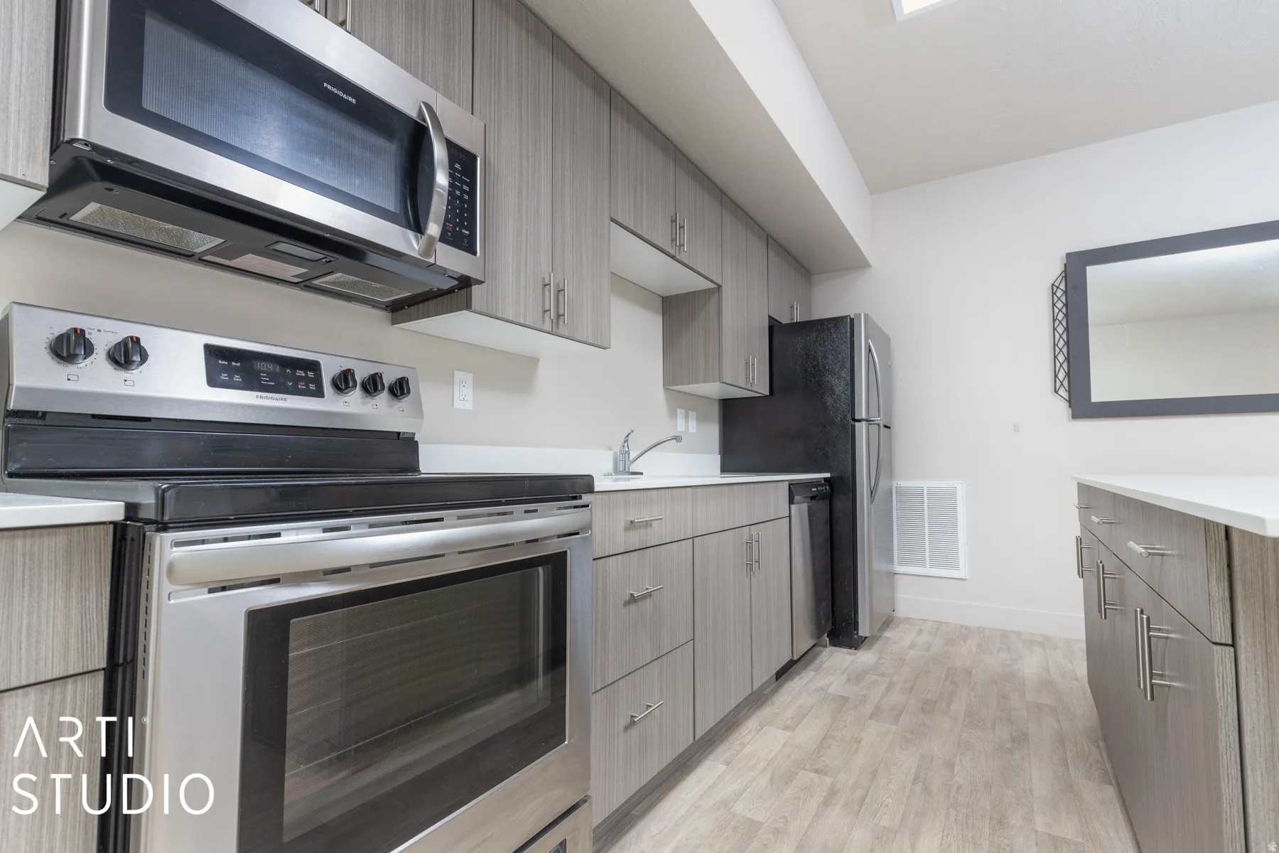 Kitchen featuring stainless steel appliances, wood-finish flooring, light gray cabinetry, and white countertops
