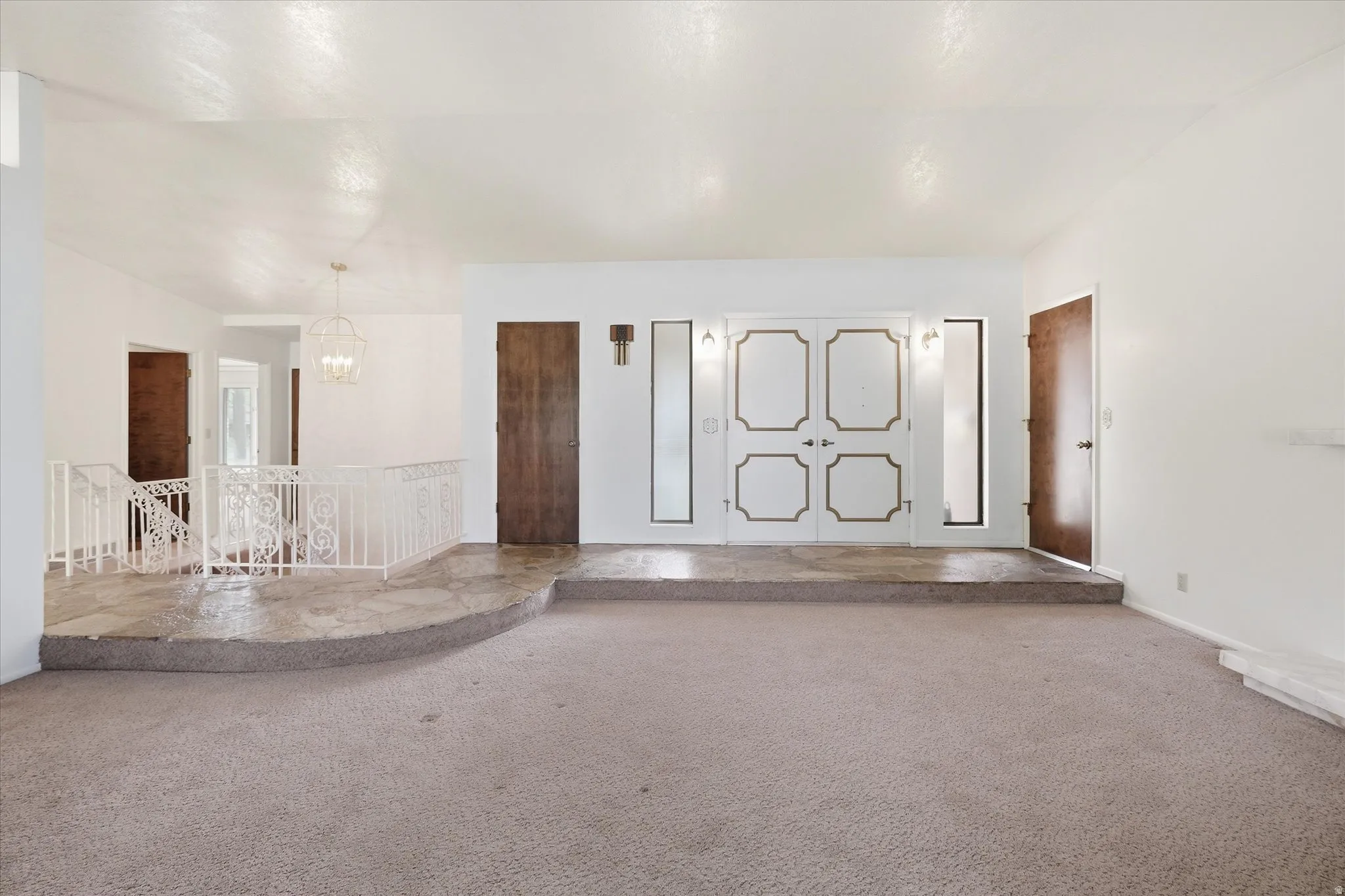 Spacious room featuring carpeting and a raised entry area with stone flooring