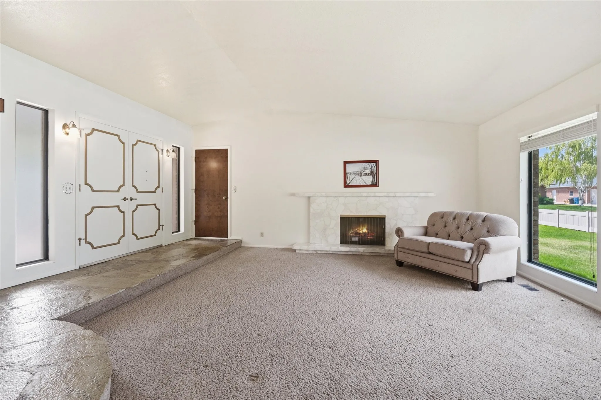 Spacious living area featuring a stone-clad fireplace and a large picture window