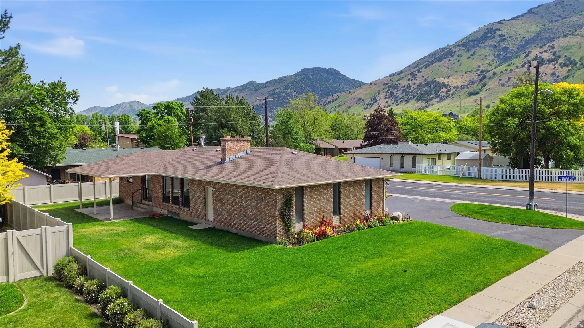 Brick exterior residence with a brown shingle roof, featuring a covered patio, fenced backyard, and a paved driveway