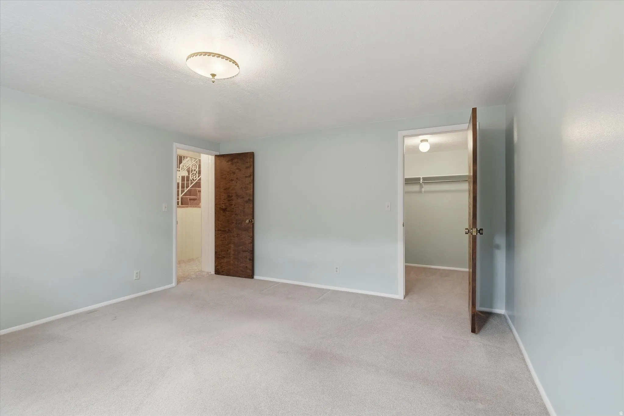 Carpeted room featuring light blue walls, a ceiling-mounted light fixture, and two wooden doors