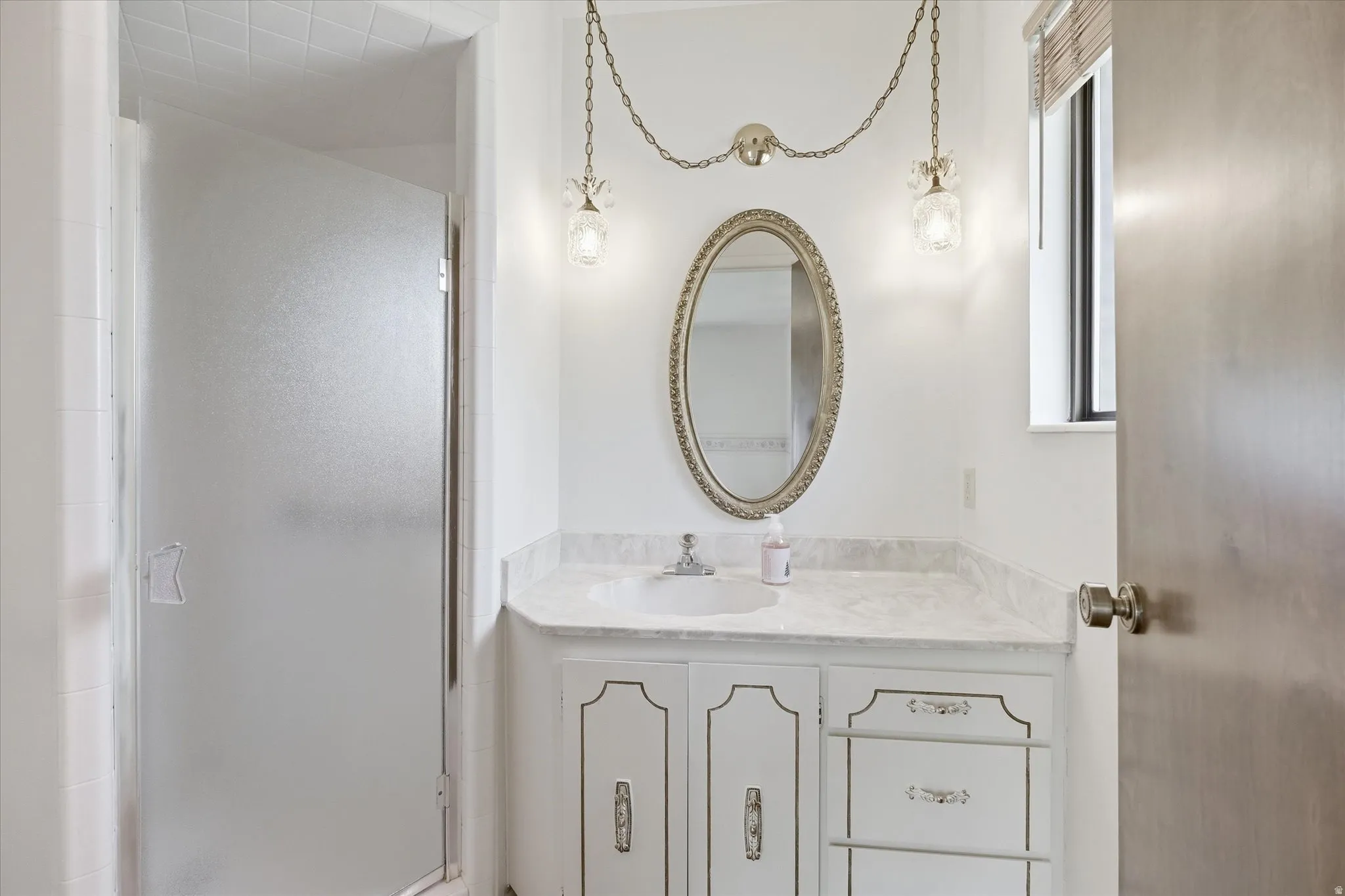 Bathroom vanity featuring a single basin, stone countertop, and decorative mirror