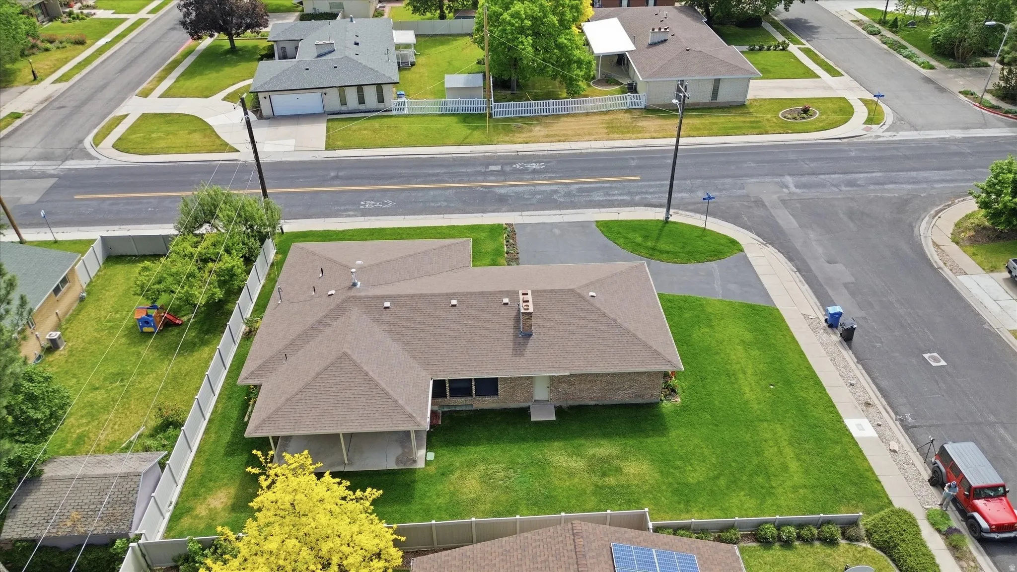 Single-story residence featuring a shingle roof, brick exterior, and an expansive green lawn
