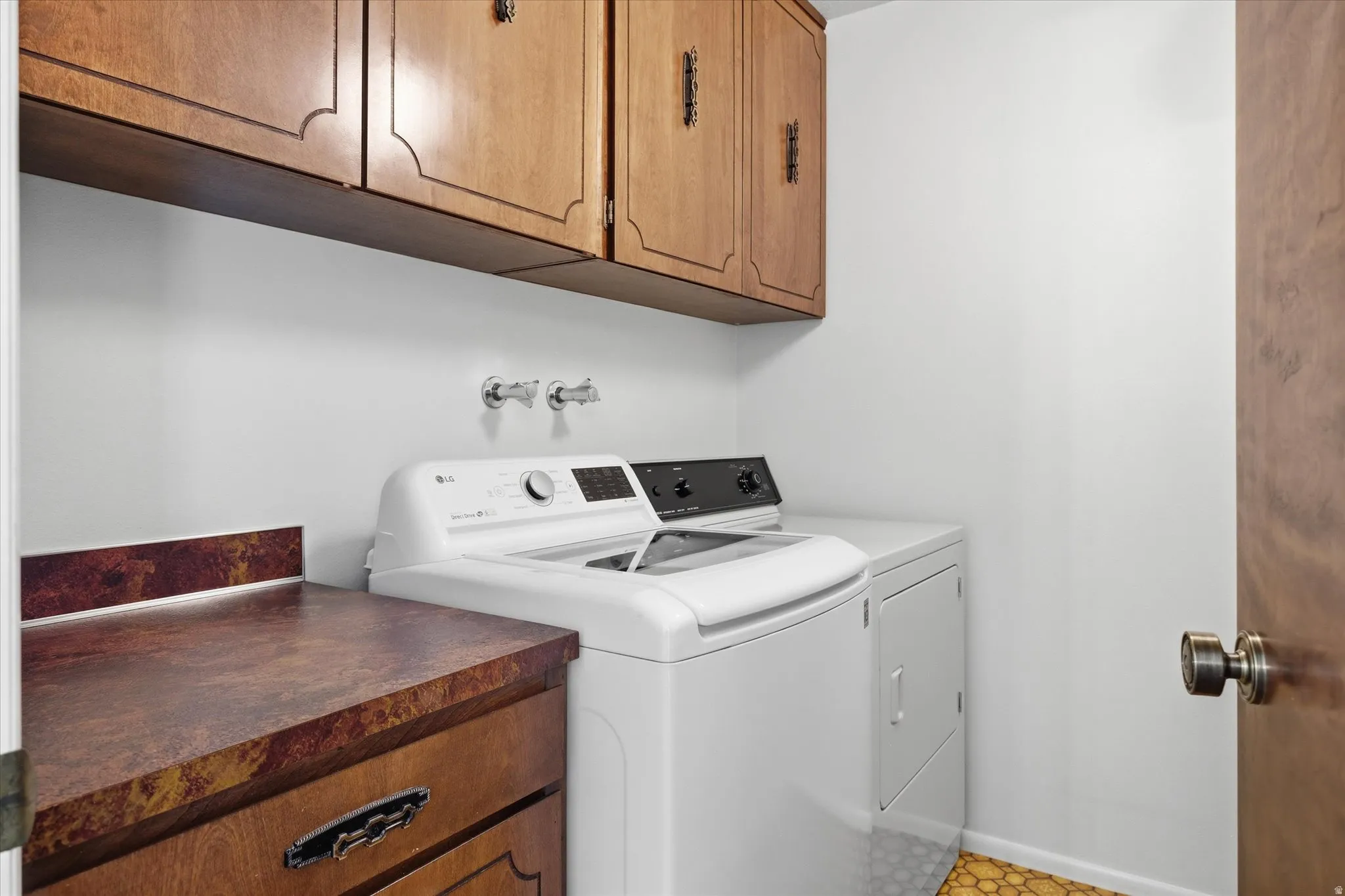Laundry area with overhead wood cabinetry, a built-in countertop, and a wood-finish door