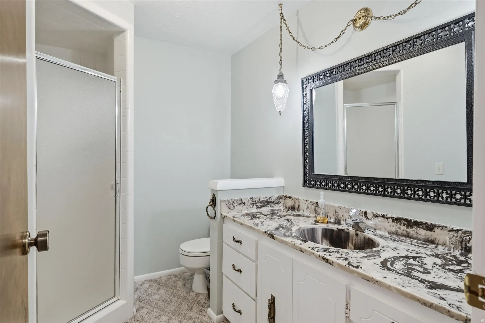 Bathroom vanity featuring a patterned countertop with integrated sink, white cabinetry, and an ornate framed mirror