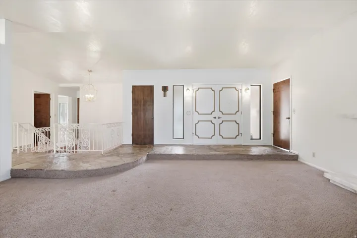 Spacious room featuring carpeting and a raised entry area with stone flooring