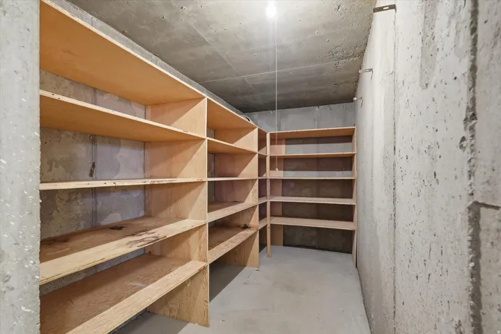 Concrete-walled storage area featuring extensive built-in wooden shelving