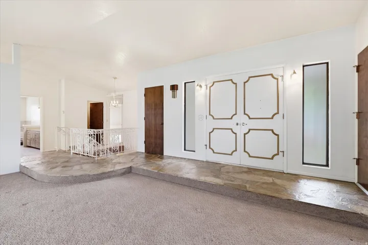 Entryway featuring double doors with decorative gold trim, flanked by vertical windows