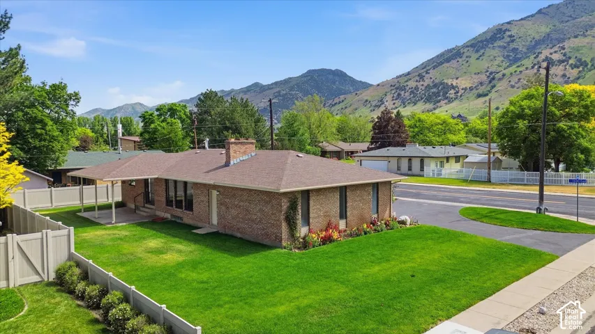 Brick exterior residence with a brown shingle roof, featuring a covered patio, fenced backyard, and a paved driveway