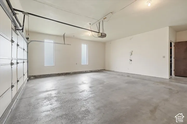 Spacious garage featuring a concrete floor, two vertical windows for natural light, and an overhead garage door opener mechanism