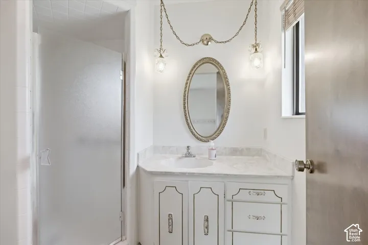 Bathroom vanity featuring a single basin, stone countertop, and decorative mirror
