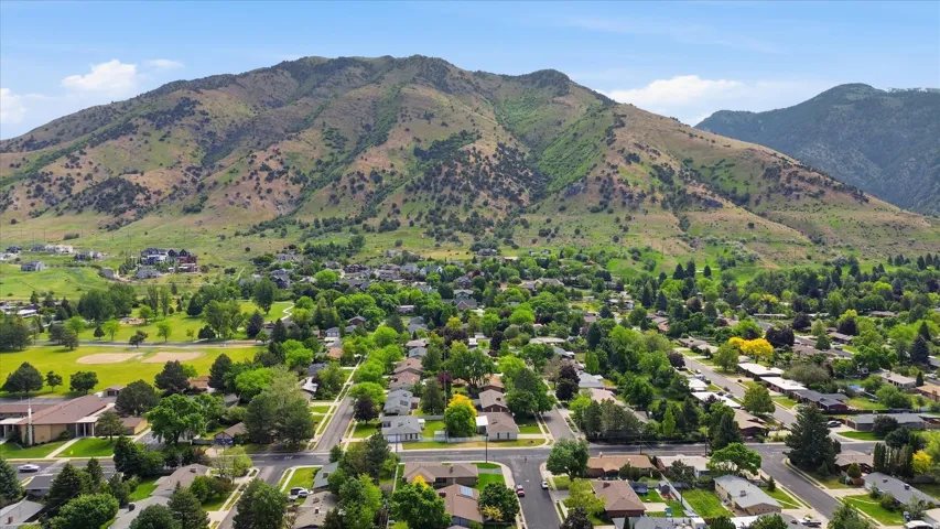 Expansive neighborhood setting featuring a mountainous backdrop, mature trees, and residential streets