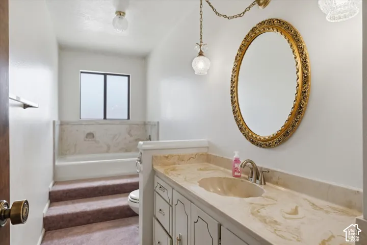 Vanity featuring a stone countertop with an integrated sink and a classic gold-framed mirror