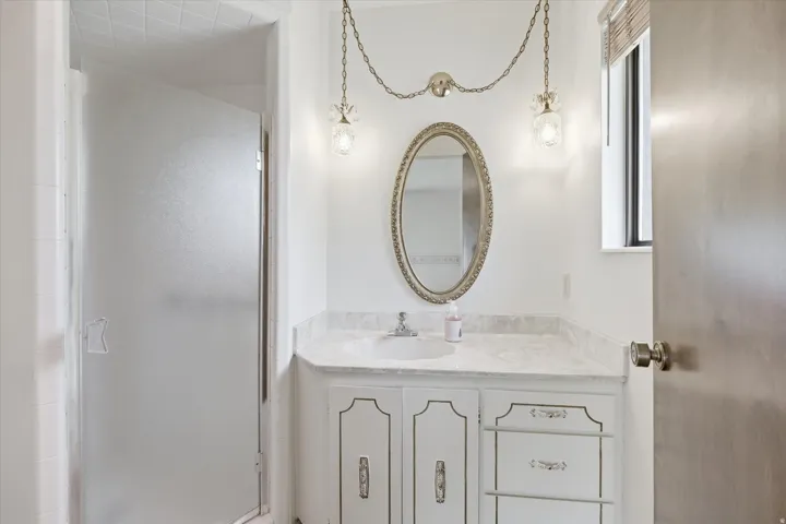 Bathroom vanity featuring a single basin, stone countertop, and decorative mirror