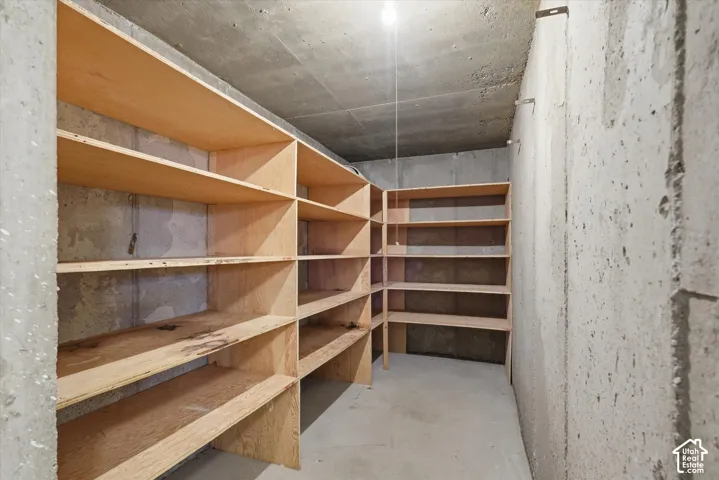 Concrete-walled storage area featuring extensive built-in wooden shelving