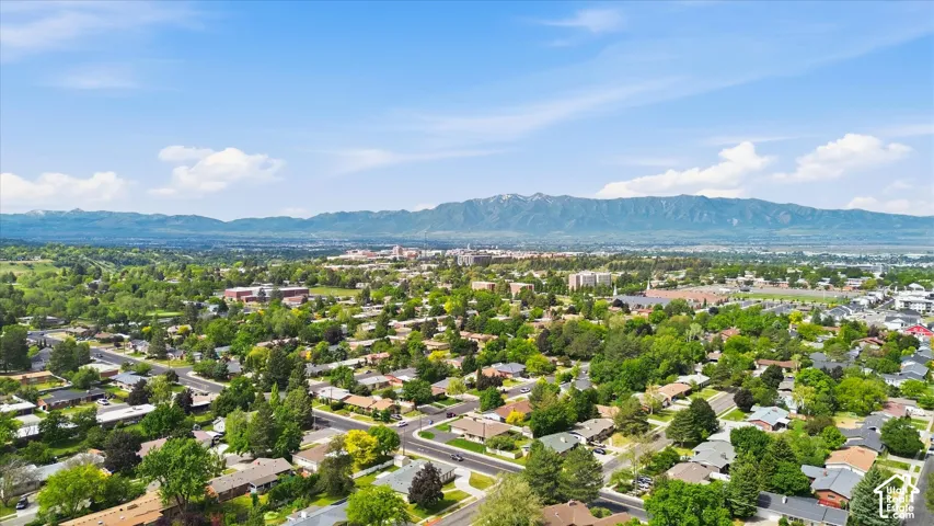 Aerial perspective showcasing a residential area with mature trees and a distant mountain range under a clear sky