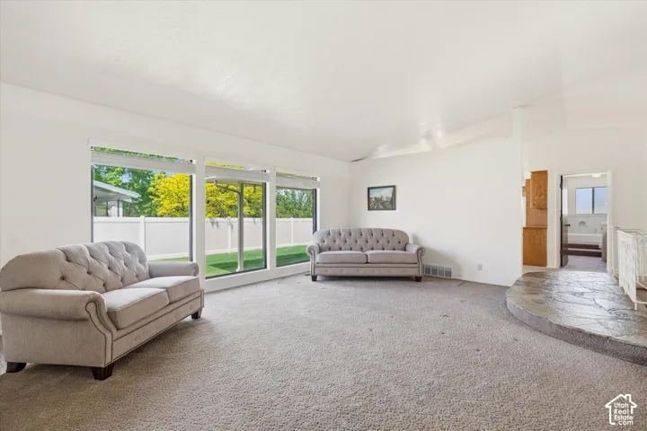 Spacious interior featuring large picture windows overlooking a fenced rear yard with mature trees