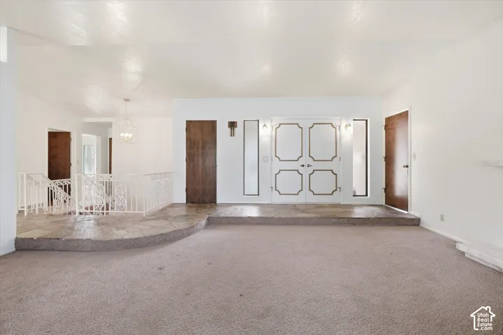 Spacious room featuring carpeting and a raised entry area with stone flooring