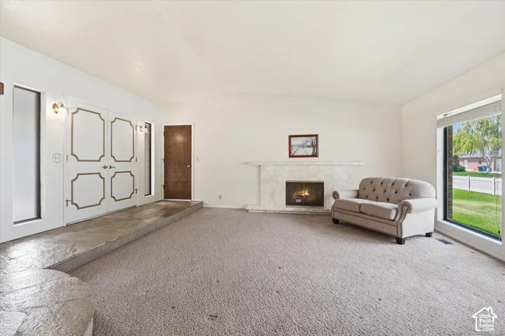 Spacious living area featuring a stone-clad fireplace and a large picture window
