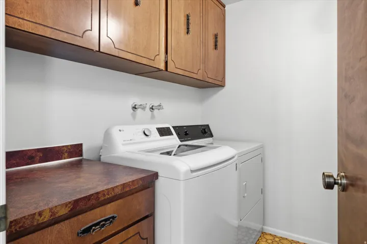 Laundry area with overhead wood cabinetry, a built-in countertop, and a wood-finish door