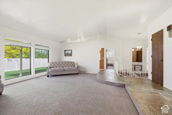 Spacious living area featuring large picture windows, vaulted ceilings, and light-toned carpeting