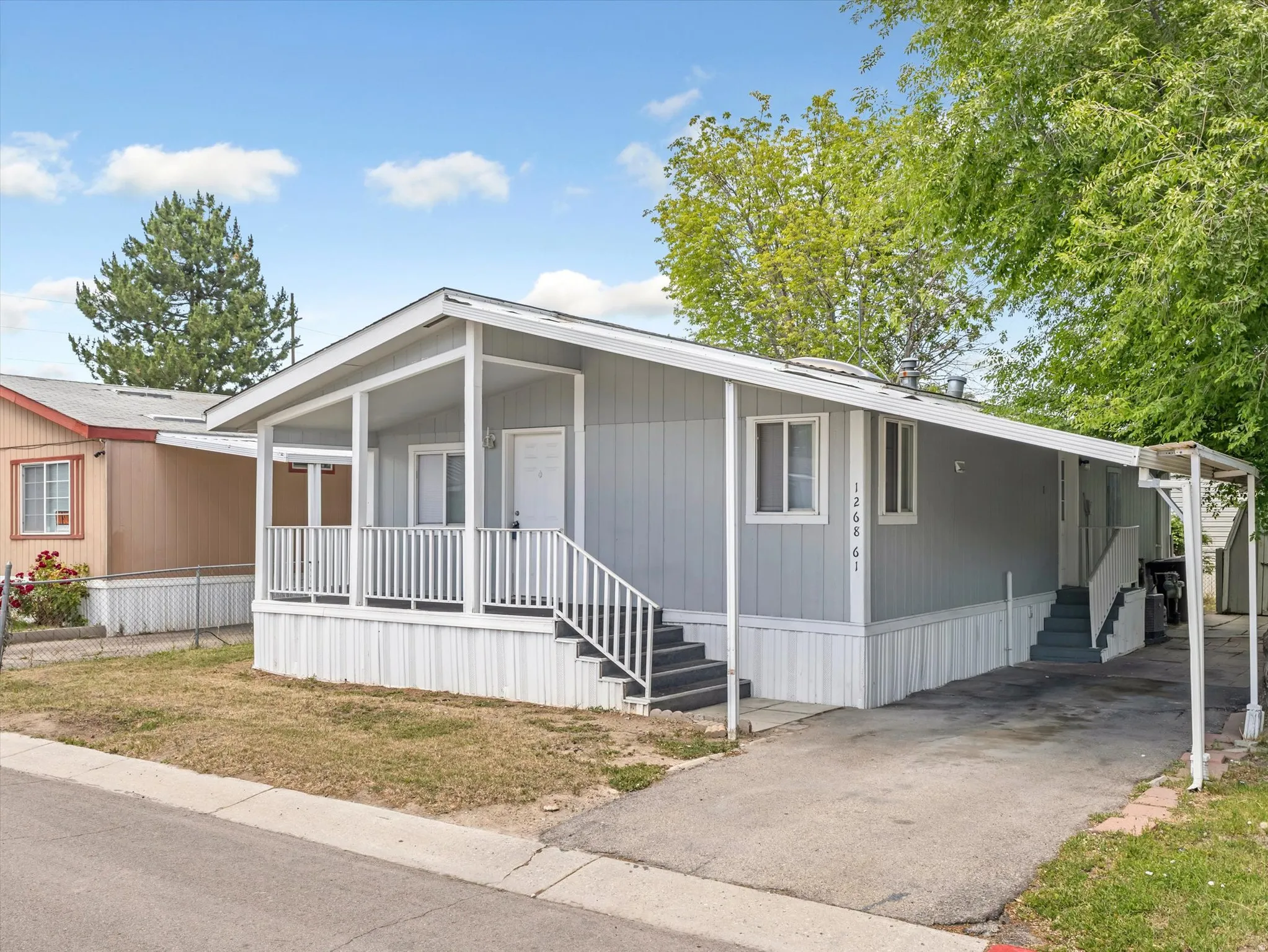 Light gray exterior with white trim, featuring a covered front porch with white railings and steps