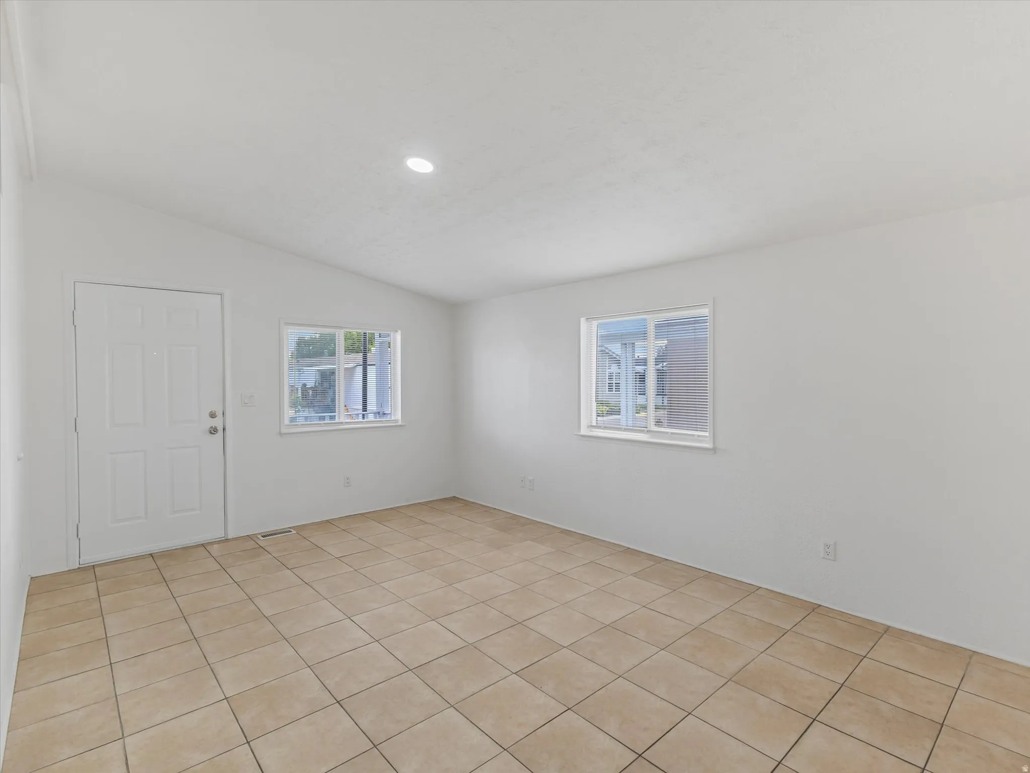 Spacious room featuring tile flooring, white walls, and multiple windows
