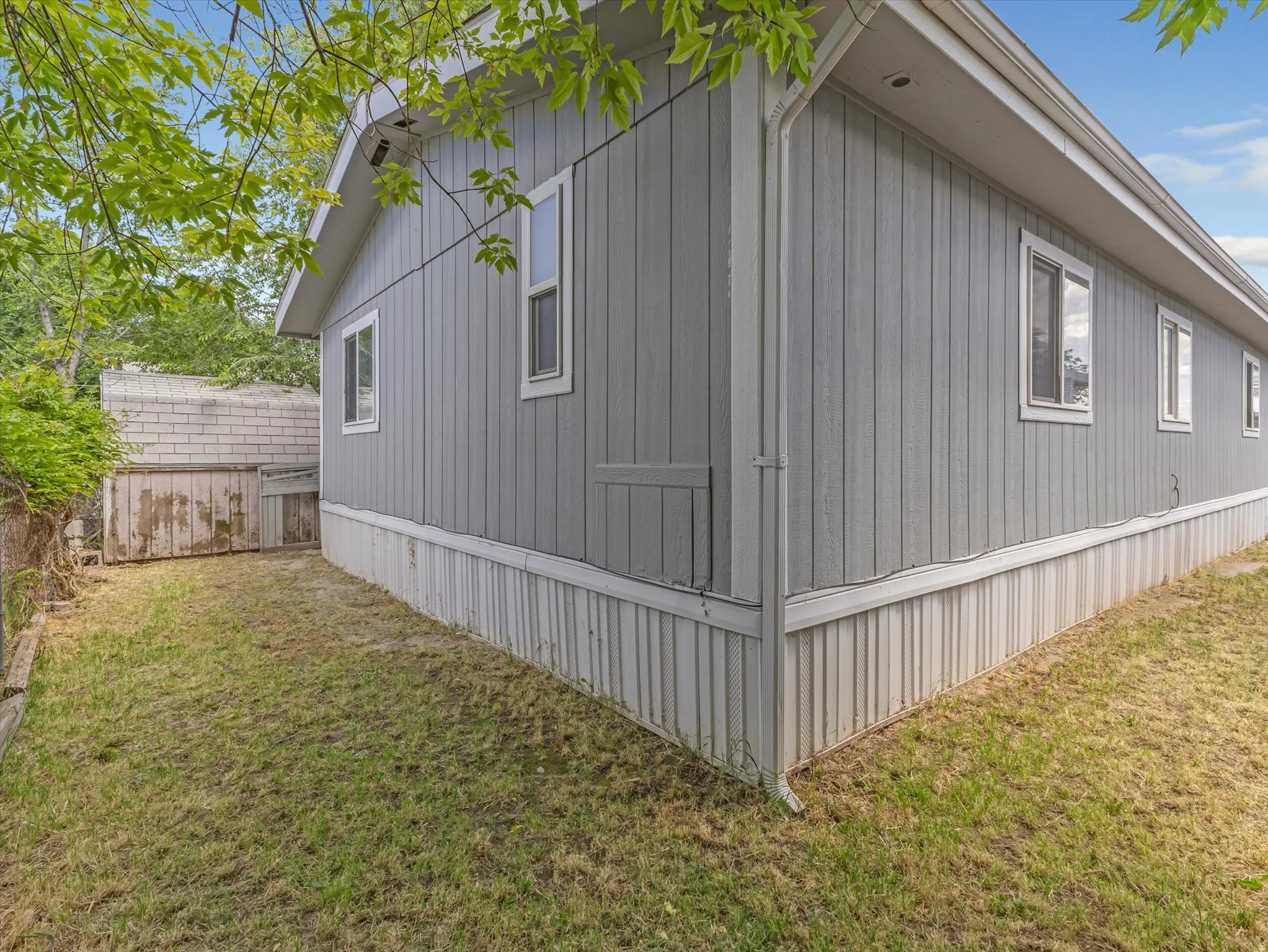 Gray vertical siding exterior with white window frames and a matching trim